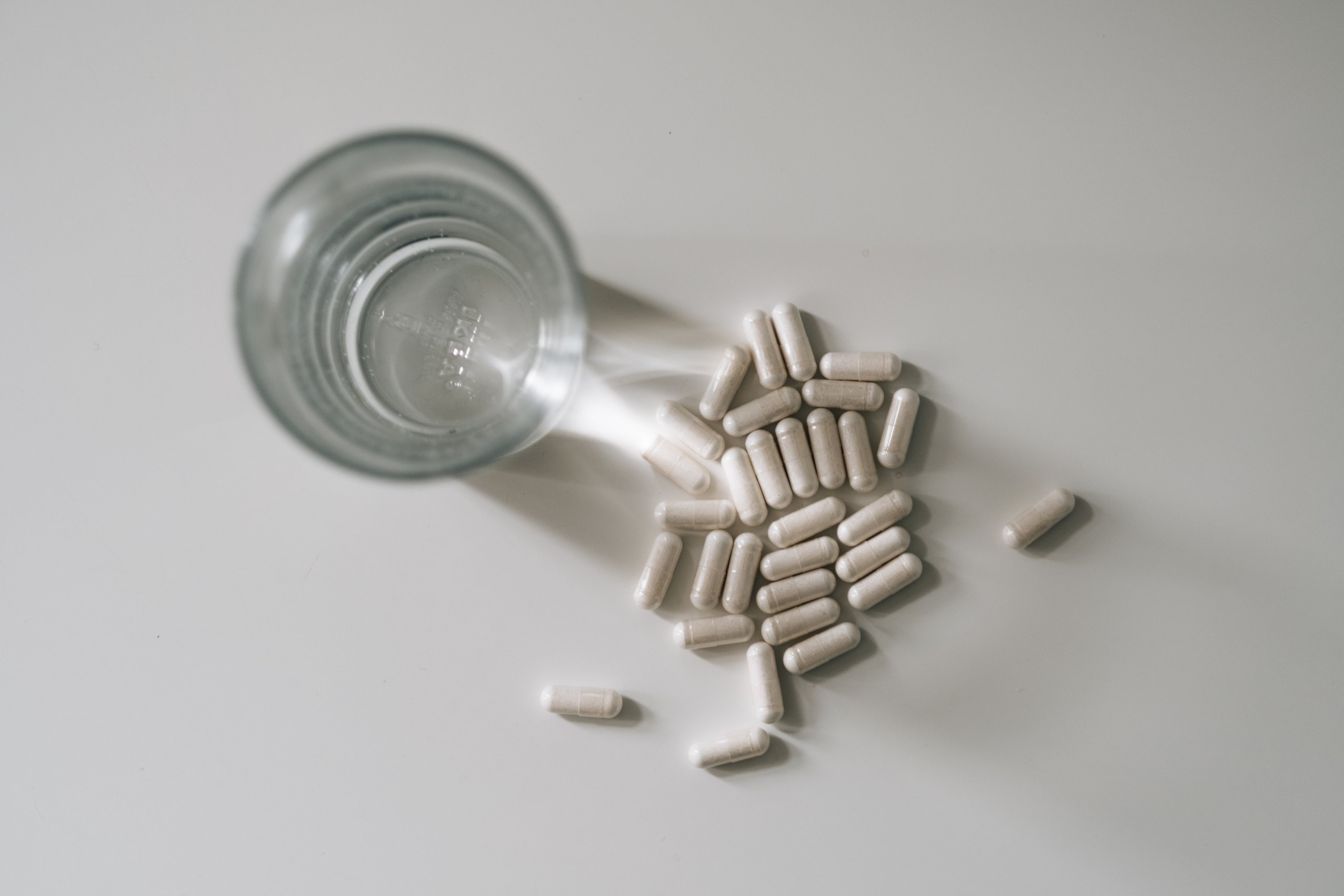 top-view-of-a-glass-of-water-and-pills-on-white-table.jpg